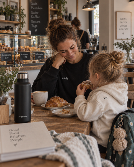 Mutter und Kind frühstücken im Café, beide in JoisPulse Kleidung