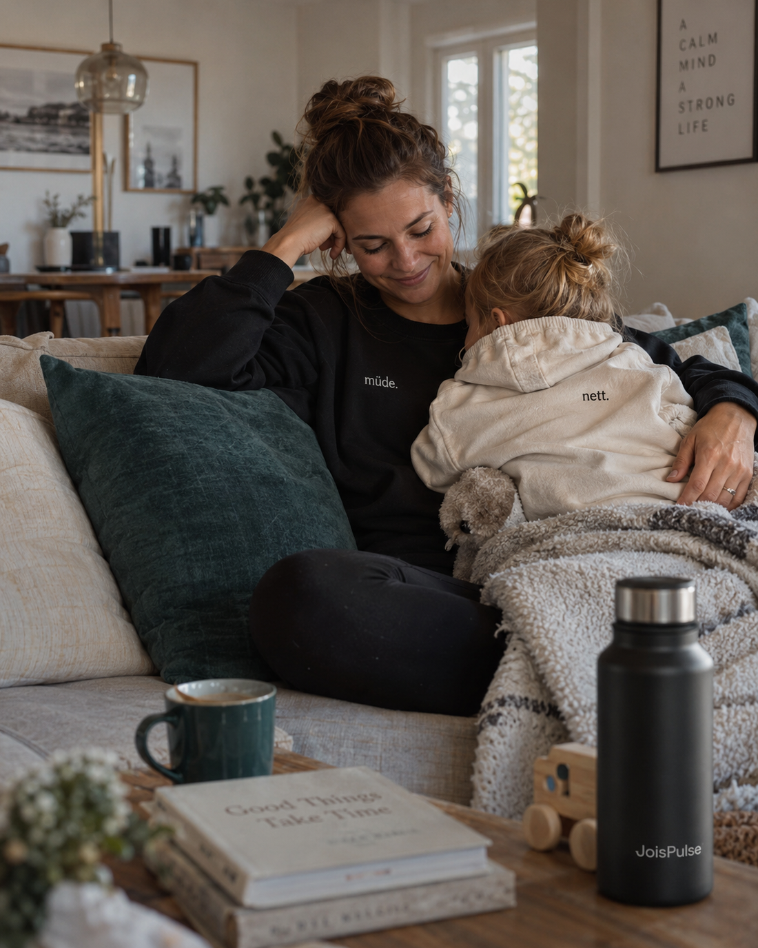 Mutter und Kind kuscheln auf dem Sofa, daneben die JoisPulse Thermoflasche