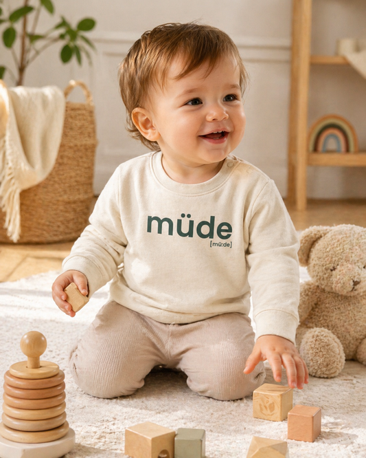 Baby mit Spielzeug im JoisPulse Baby Sweatshirt mit dem Statement müde
