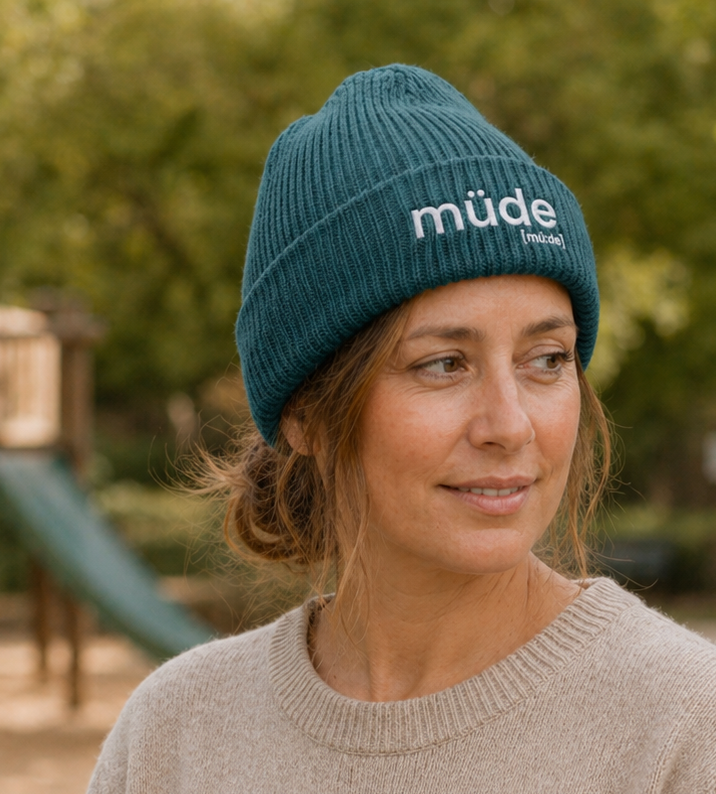 Frau mit Kinderwagen trägt die JoisPulse Fisherman Beanie mit dem Statement müde