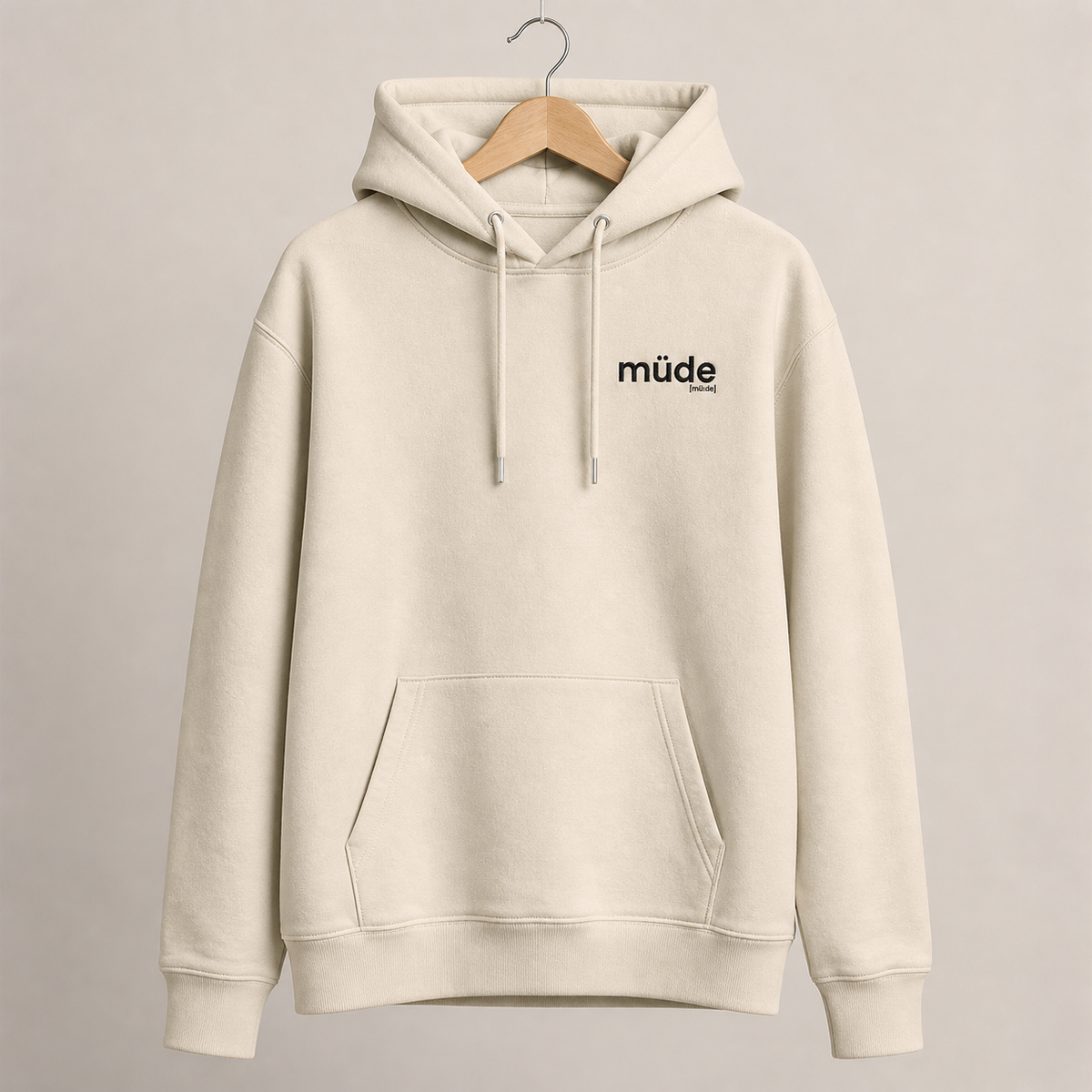 Cremefarbener Bio Hoodie müde von JoisPulse mit gesticktem Statement, flach liegend