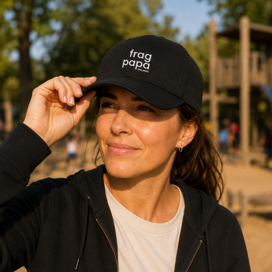Mann auf einem sonnigen Spielplatz trägt das schwarze JoisPulse Basecap mit dem Statement frag papa