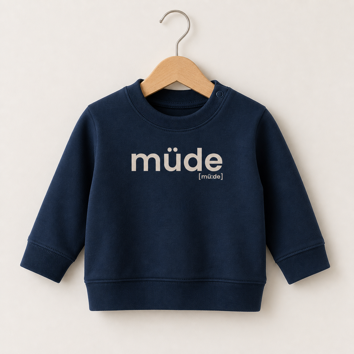 Dunkelblaues Baby Sweatshirt müde von JoisPulse auf einem Holzbügel