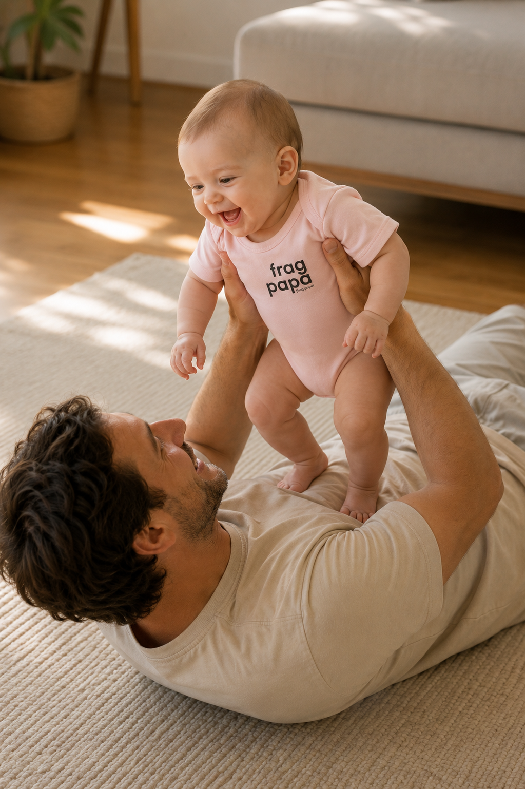 Vater hält sein lachendes Baby hoch, das Baby trägt den JoisPulse Body mit dem Statement frag papa