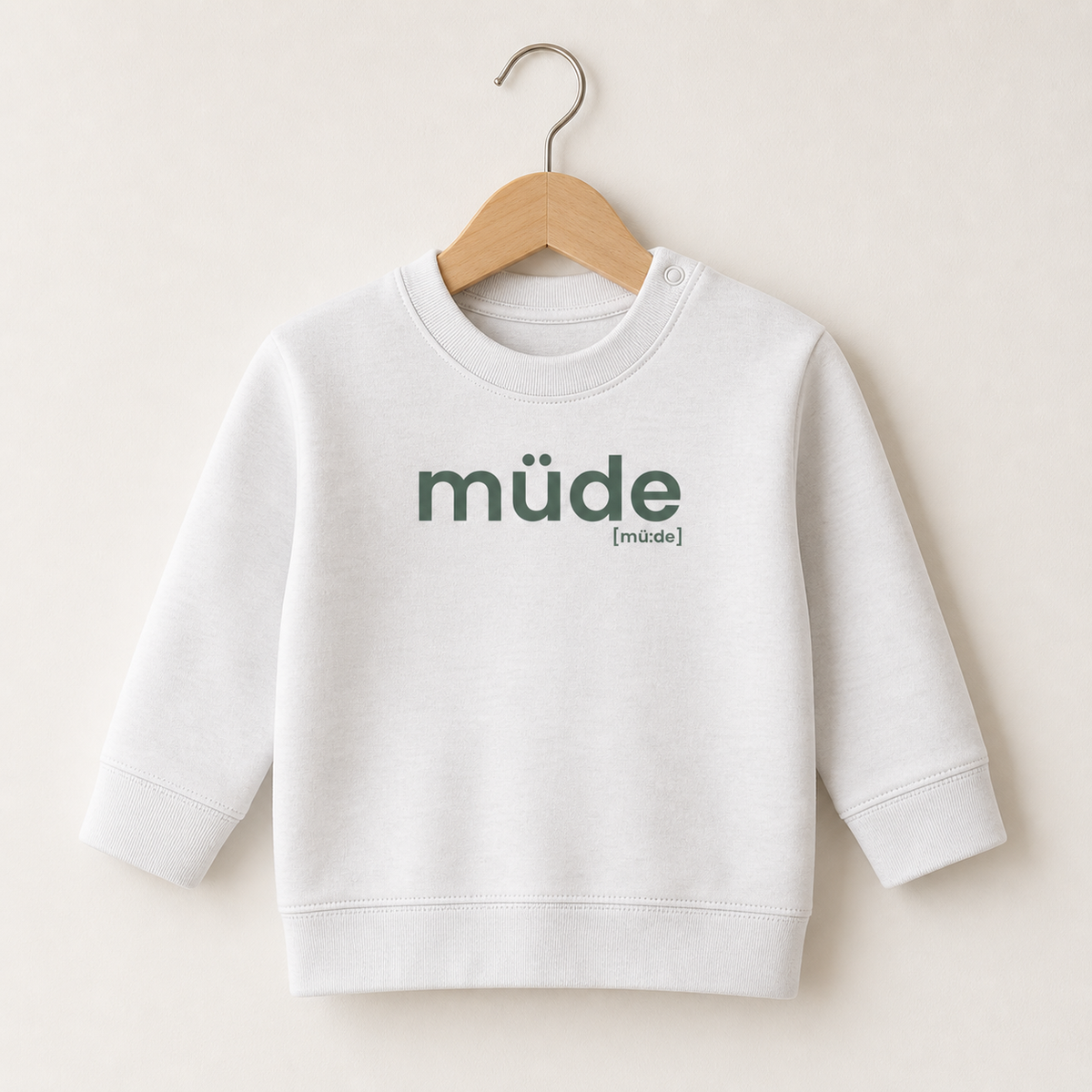 Weißes Baby Sweatshirt müde von JoisPulse auf einem Holzbügel