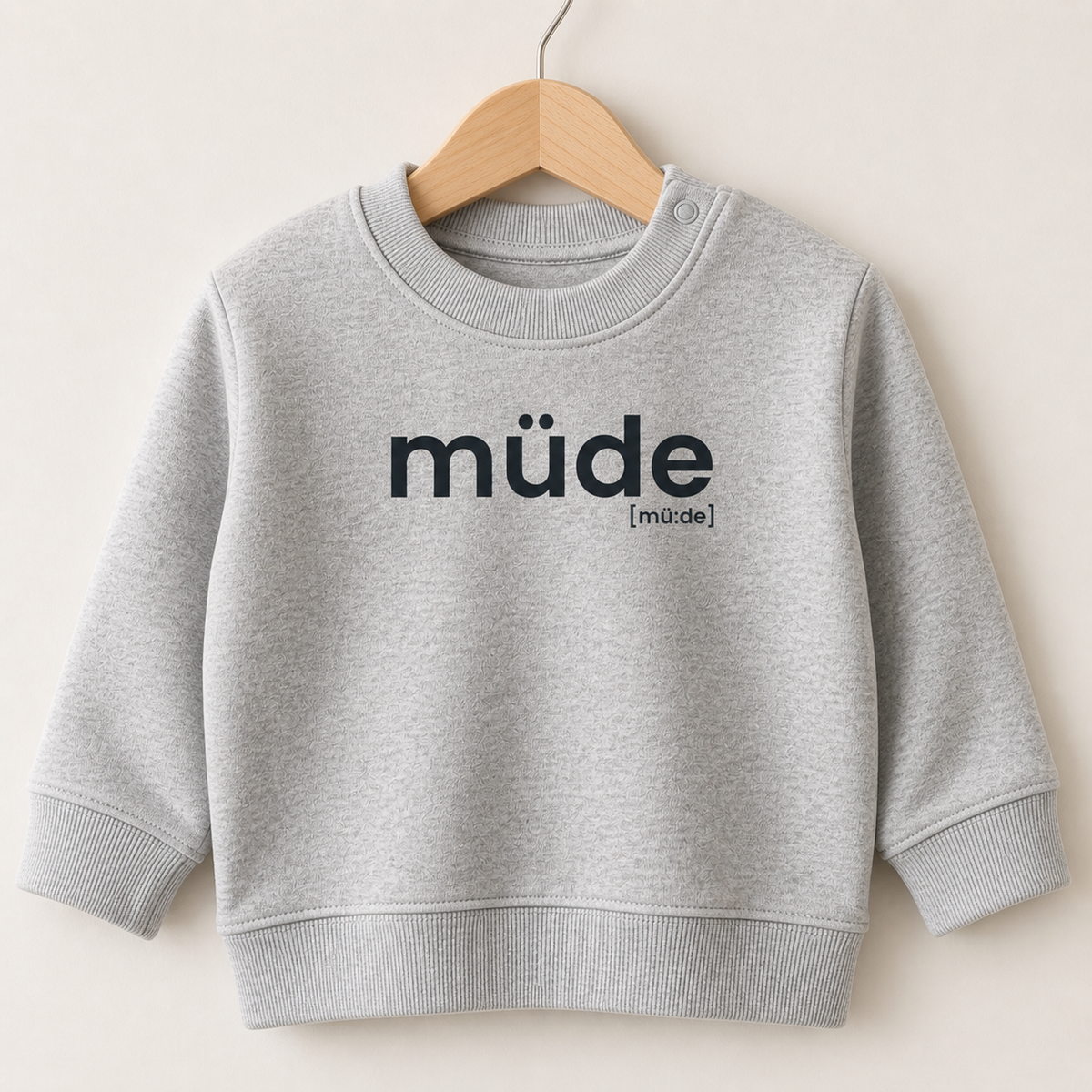 Graues Baby Sweatshirt müde von JoisPulse auf einem Holzbügel